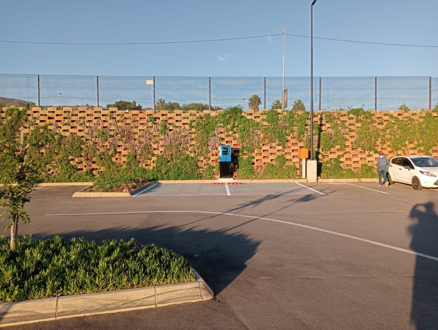 EV charger installed against a landscaped green wall in a parking area